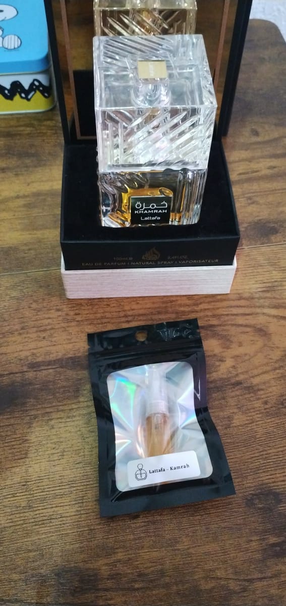 Decant sellado en su bolsita holográfica junto al perfume original